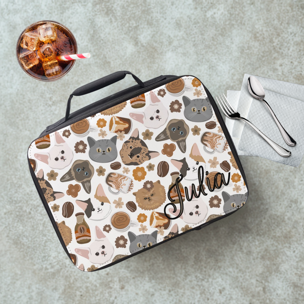 Lunch bag with cat pattern and 'Julia' branding on a cafeteria table with a drink and utensils.