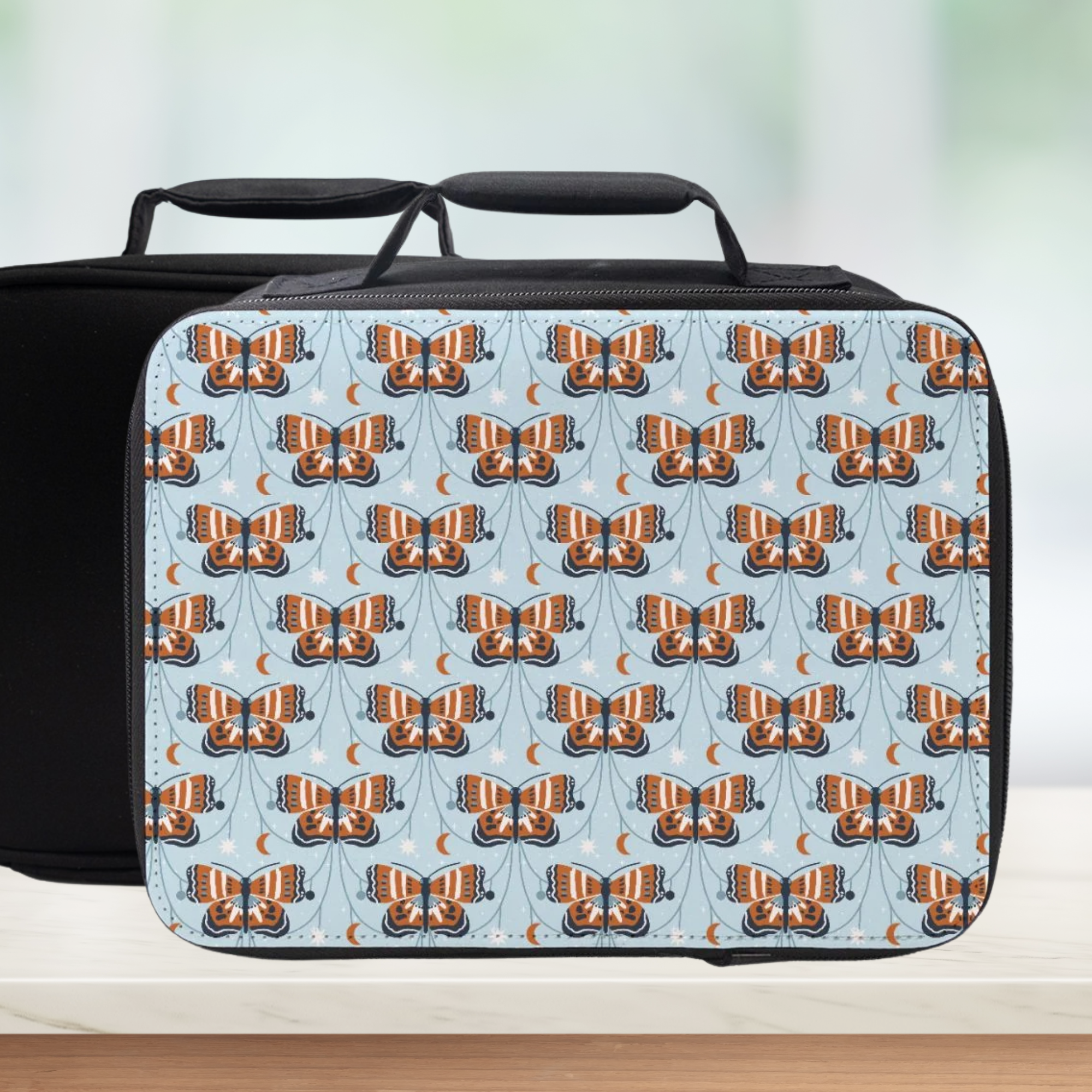 Black lunch bag with butterfly pattern on a light blue background