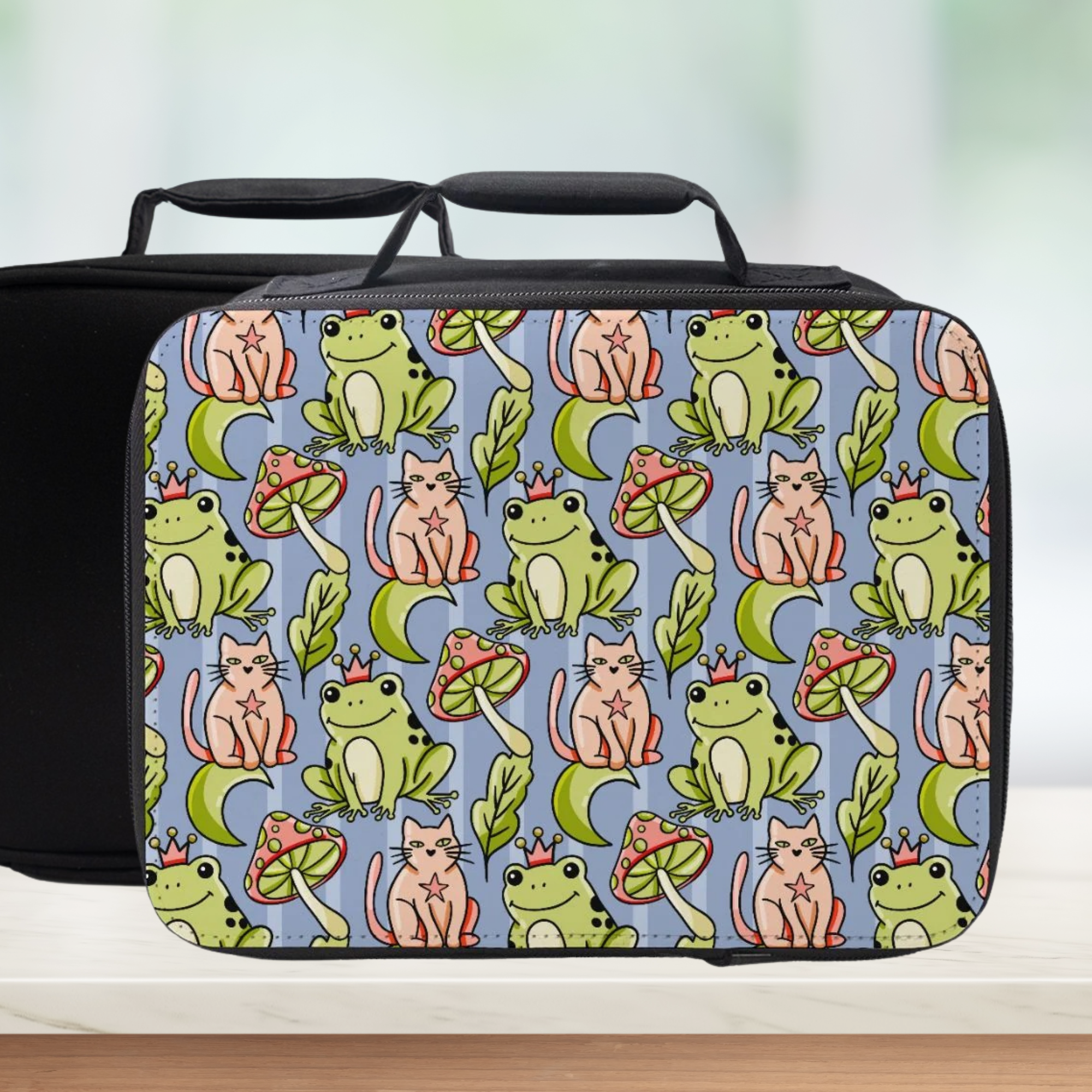 Lunch bag with a colorful pattern of frogs, cats, and mushrooms on a blue background.