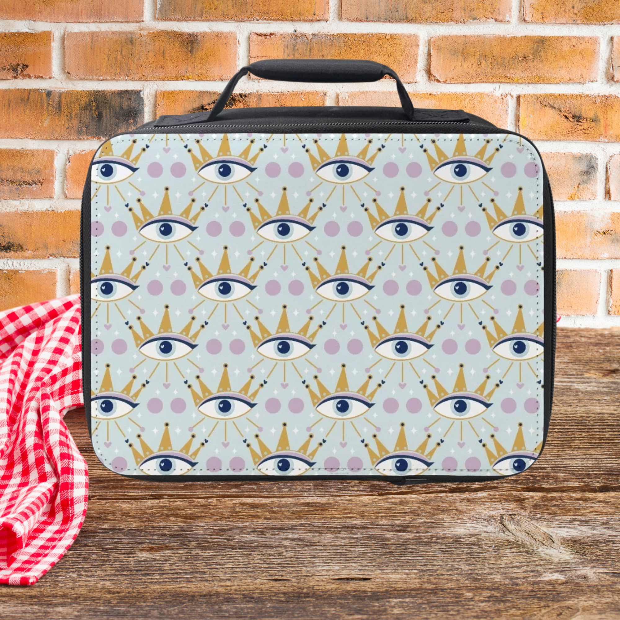 Lunch bag with a crowned eye pattern on a wooden picnic table and brick wall background
