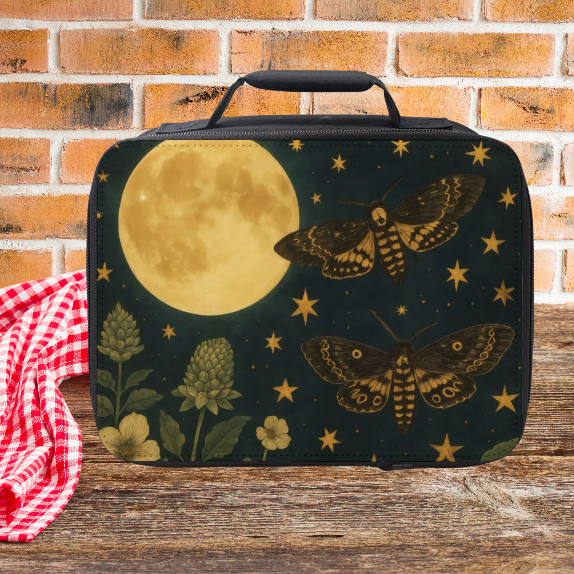  insulated lunch bag with moon, stars, and moths design on a wooden picnic table with brick wall background