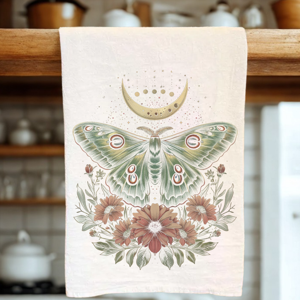 Decorative tea towel with a moth and floral design hanging on a wooden rack.