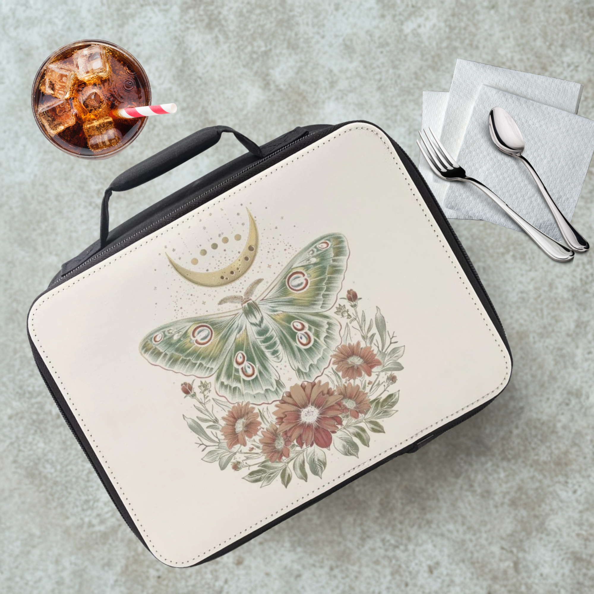  insulated lunch bag with celestial moth design on a cafeteria table with a drink and eating utensils
