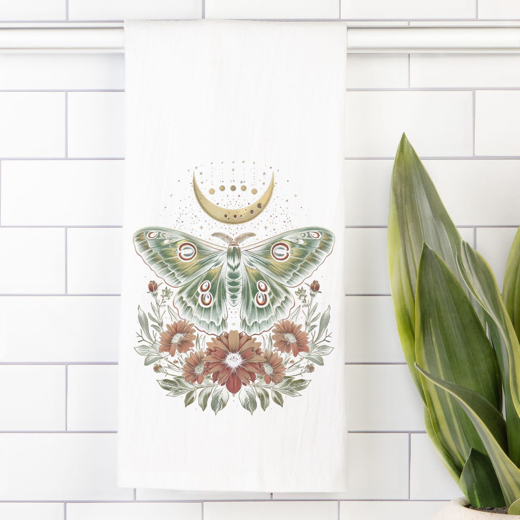 Decorative tea towel with a green moth and flowers design on a white tiled wall.