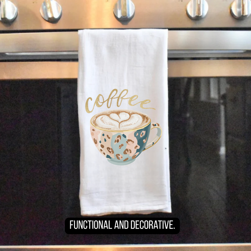 Decorative kitchen towel with a coffee cup design hanging on an oven handle.