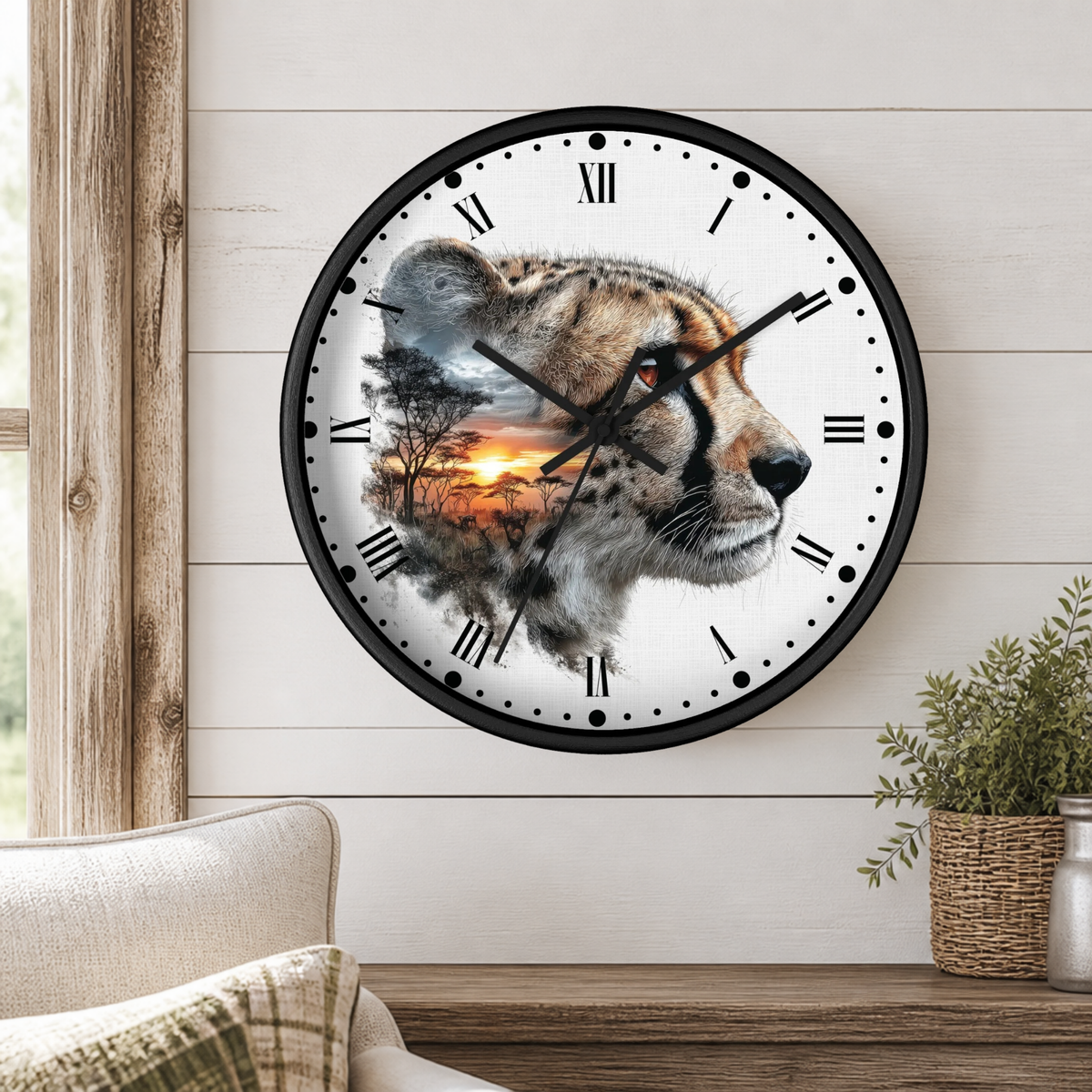 A round wall clock with a black frame and Roman numerals, featuring a printed design of a cheetah head layered over an African savanna sunset scene. The clock is mounted on a white wood-paneled wall above a wooden shelf with a small potted plant.