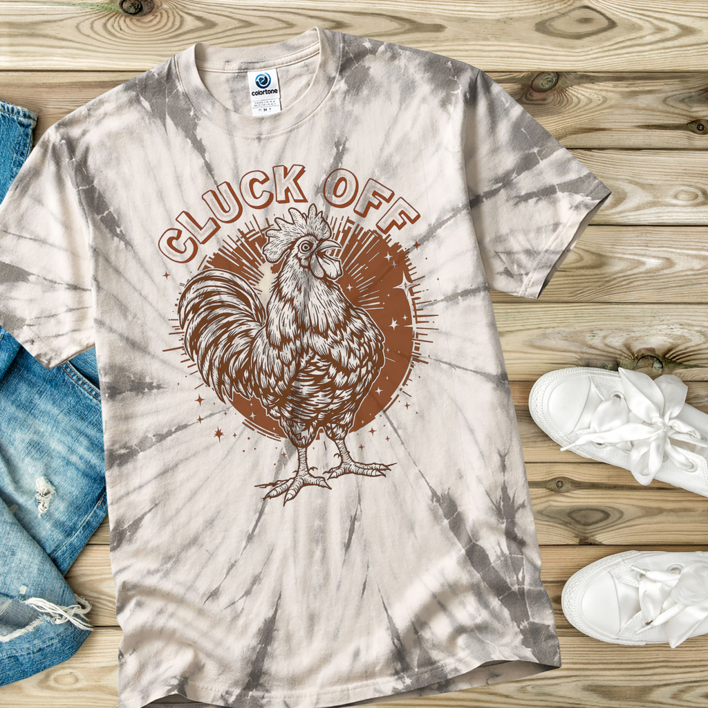 Tie-dye t-shirt with rooster graphic and 'CLUCK OFF' text on a wooden surface.