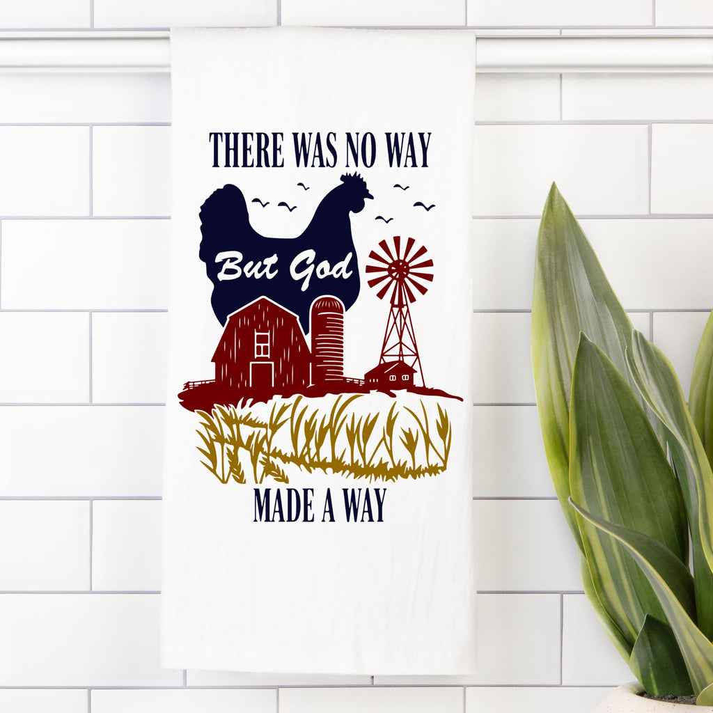 Decorative tea towel with a chicken, barn, windmill, and text on a white tiled wall.