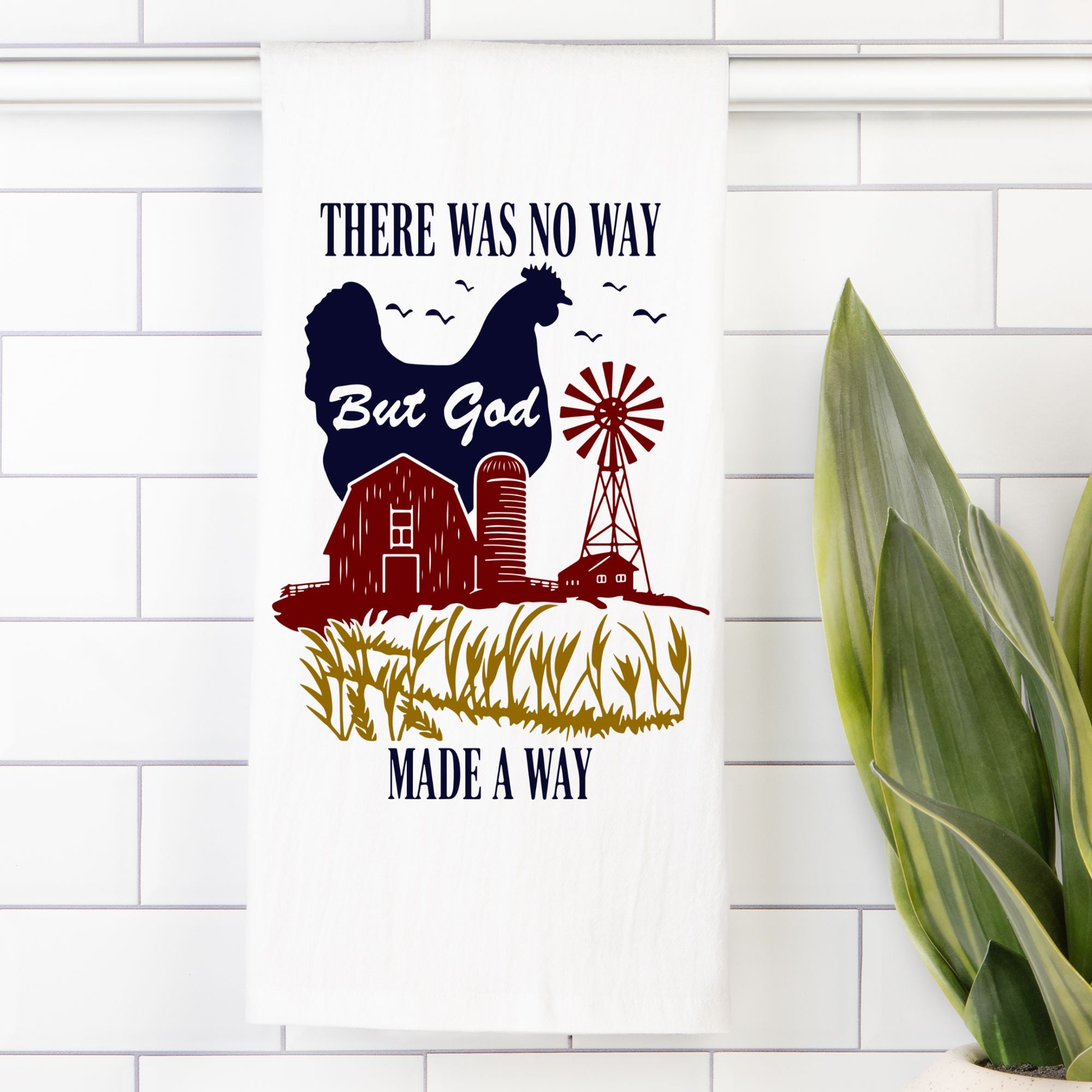 Decorative tea towel with a chicken, barn, windmill, and text on a white tiled wall.