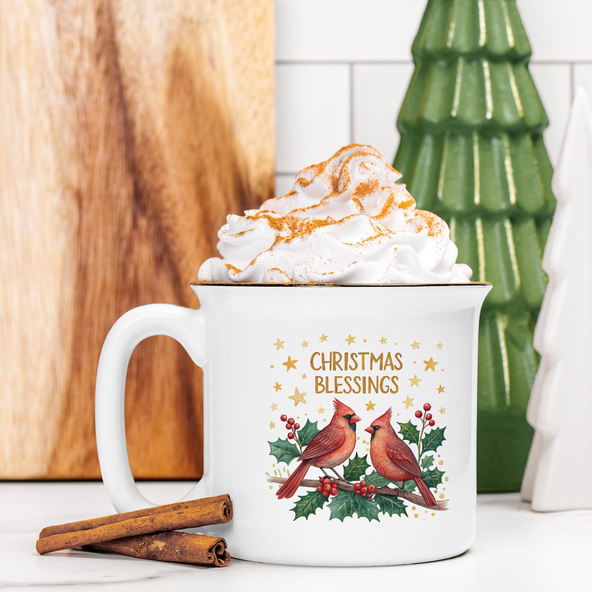 White mug with 'Christmas Blessings' text and cardinal design, filled with hot chocolate and whipped cream, on a wooden surface.