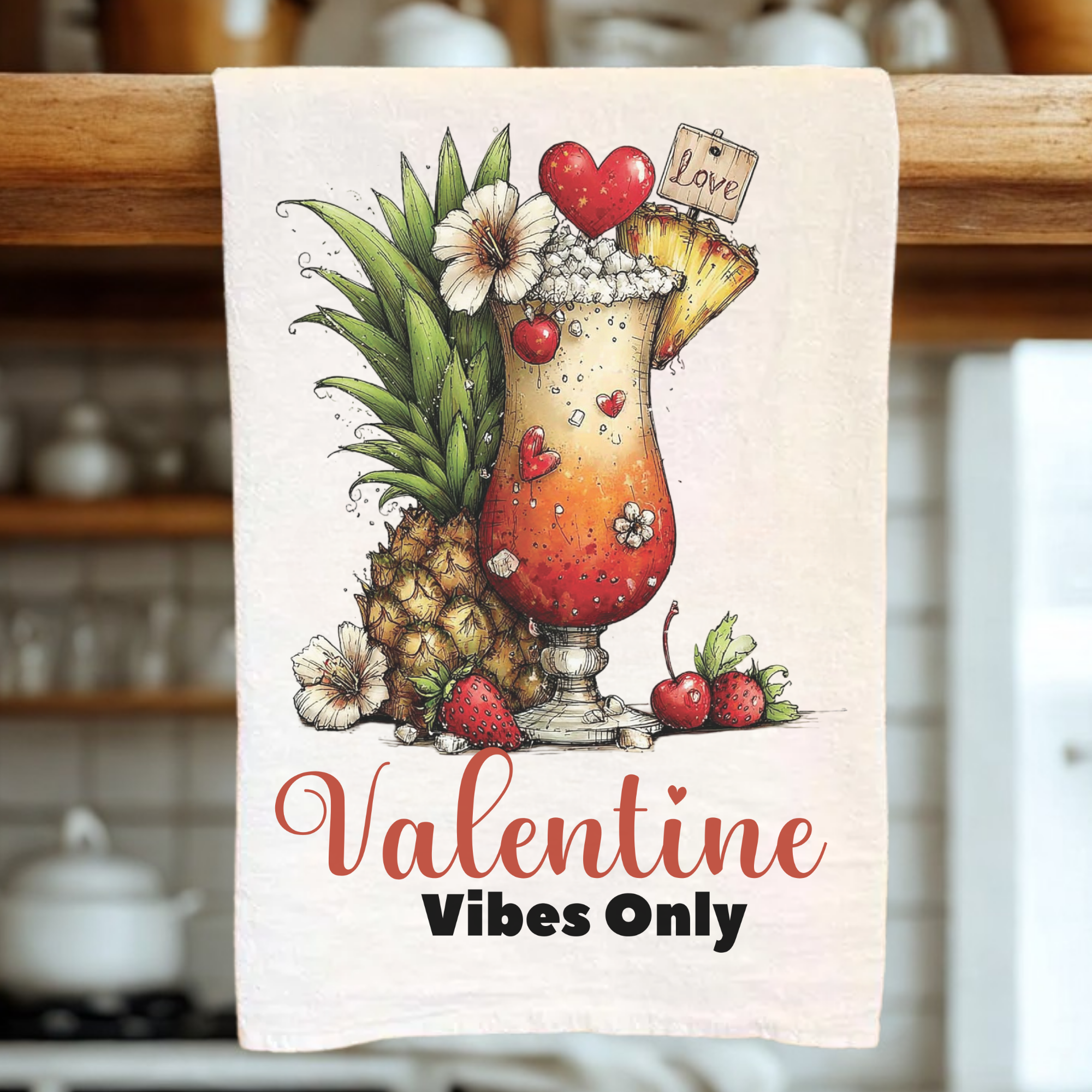 Valentine-themed towel with a cocktail and pineapple design, hanging on a wooden rack.