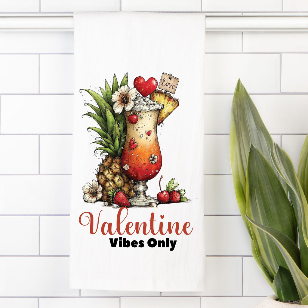 Decorative tea towel with a cocktail and pineapple design and text' Valentine Vibes Only' on a white tiled wall.