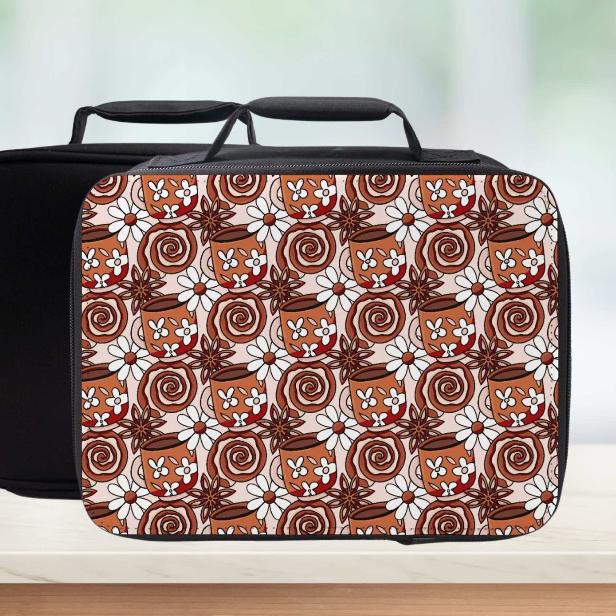 Coffee cup and cinnamon roll patterned lunch bag with black handle on a light background