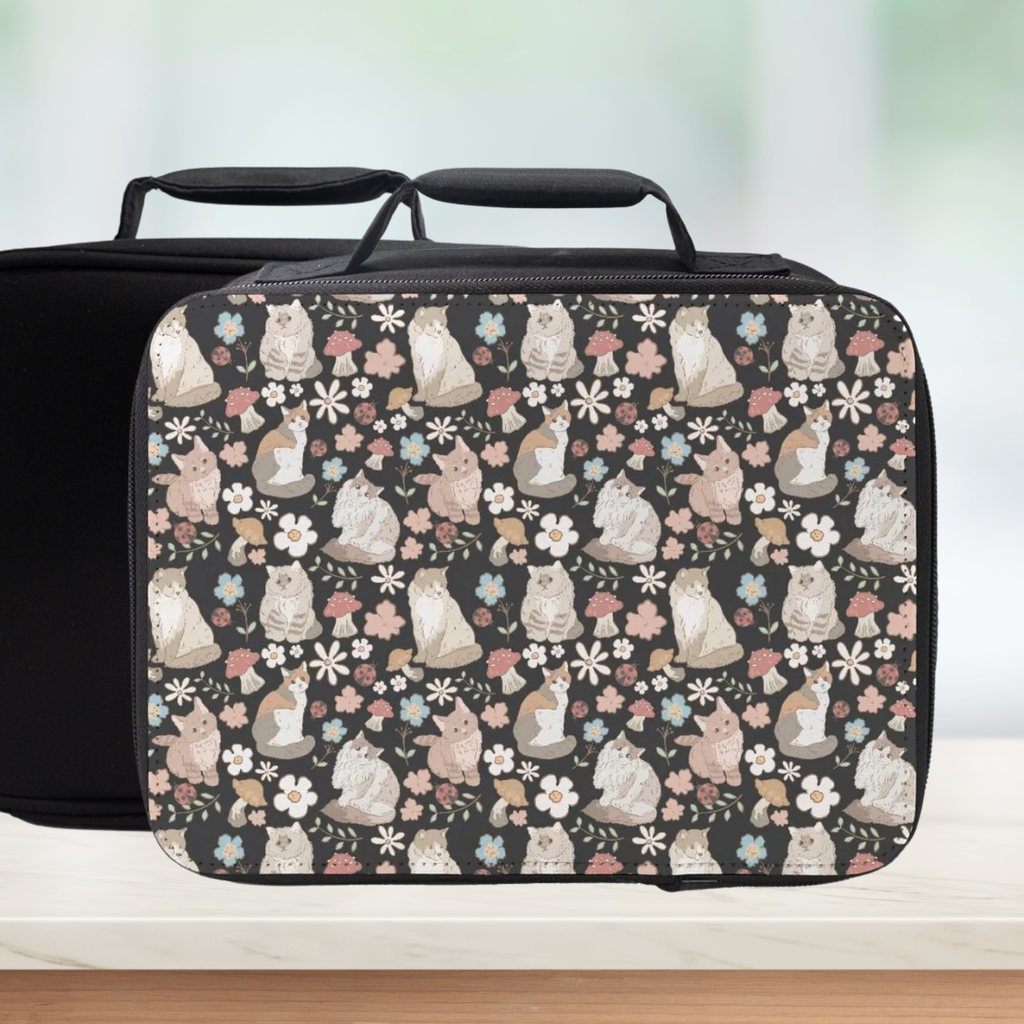 Black lunch bag with cat and floral pattern on a counter and light background