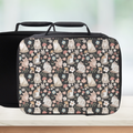 Black lunch bag with cat and floral pattern on a counter and light background