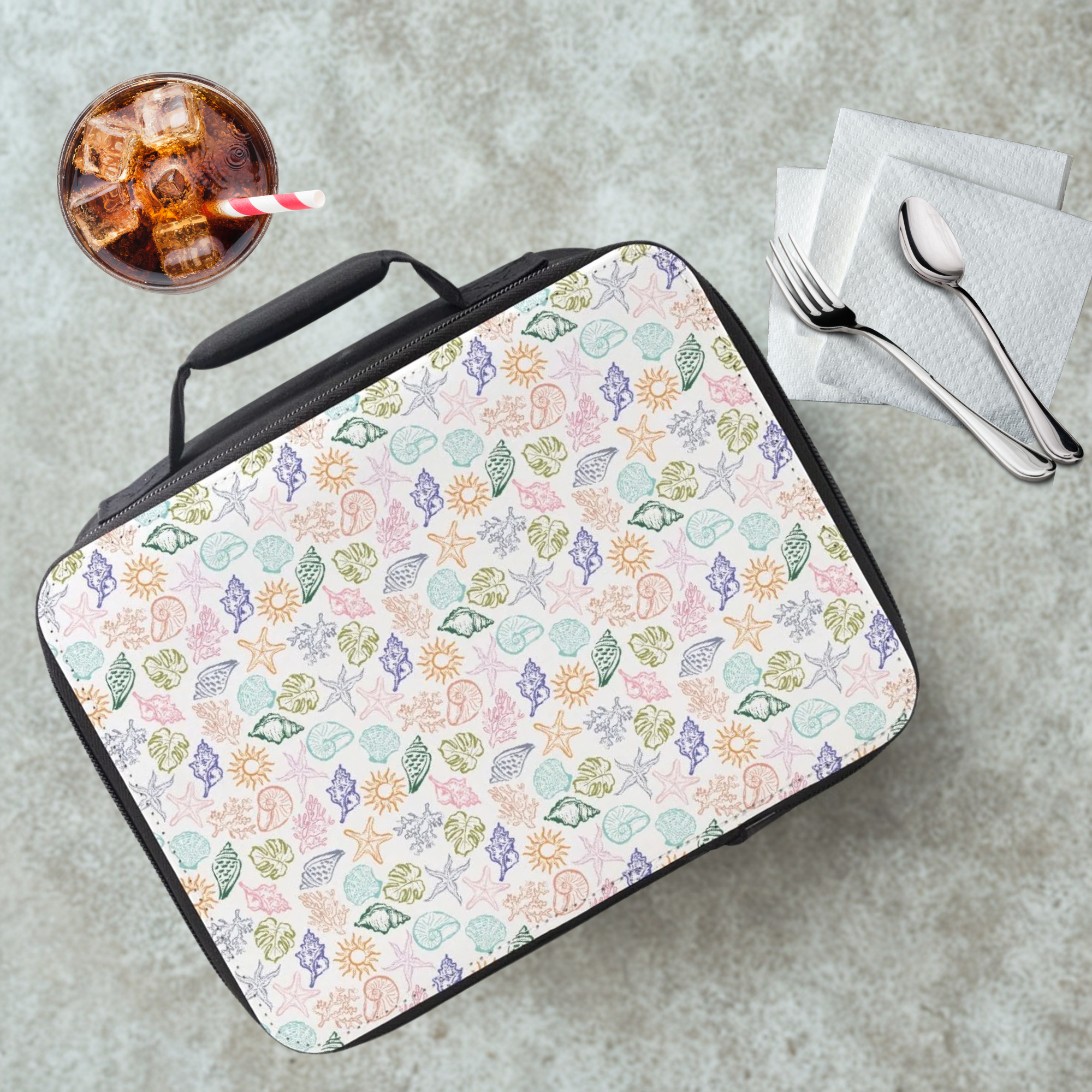 Hand drawn colorful sea shell patterned lunch bag on a cafeteria table with a drink and utensils.