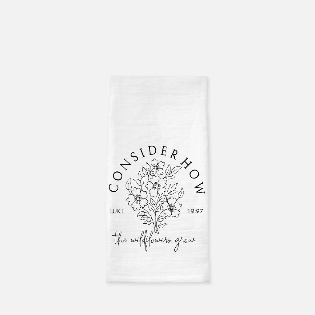 White tea towel with floral design and text 'Consider How The Wildflowers Grow' on a white background