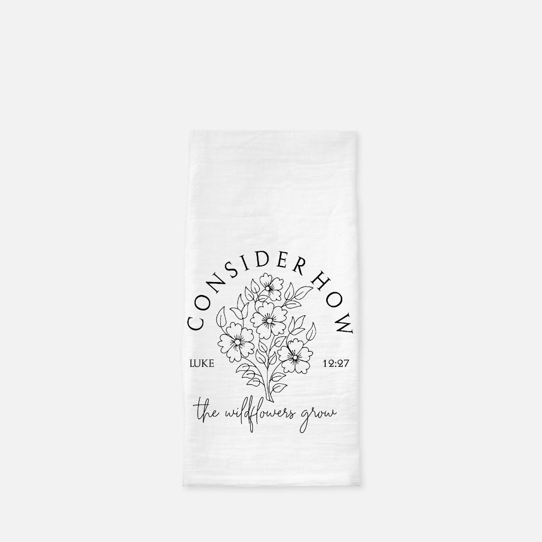 White tea towel with floral design and text 'Consider How The Wildflowers Grow' on a white background