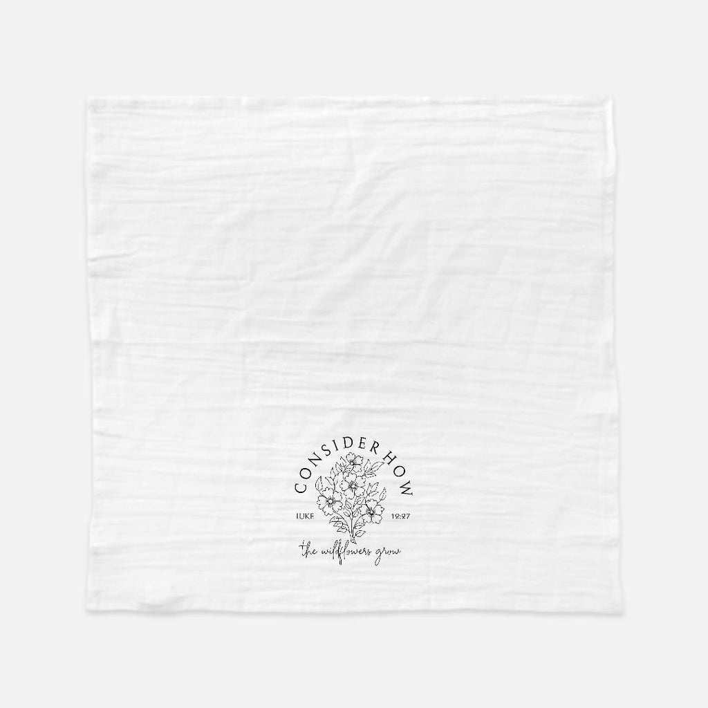 White tea towel with black floral logo design and text 'Consider How The Wildflowers Grow' on a white background