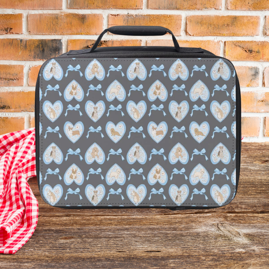  insulated lunch bag with hand drawn hearts, dogs, and bows pattern on a wooden picnic table with brick wall background