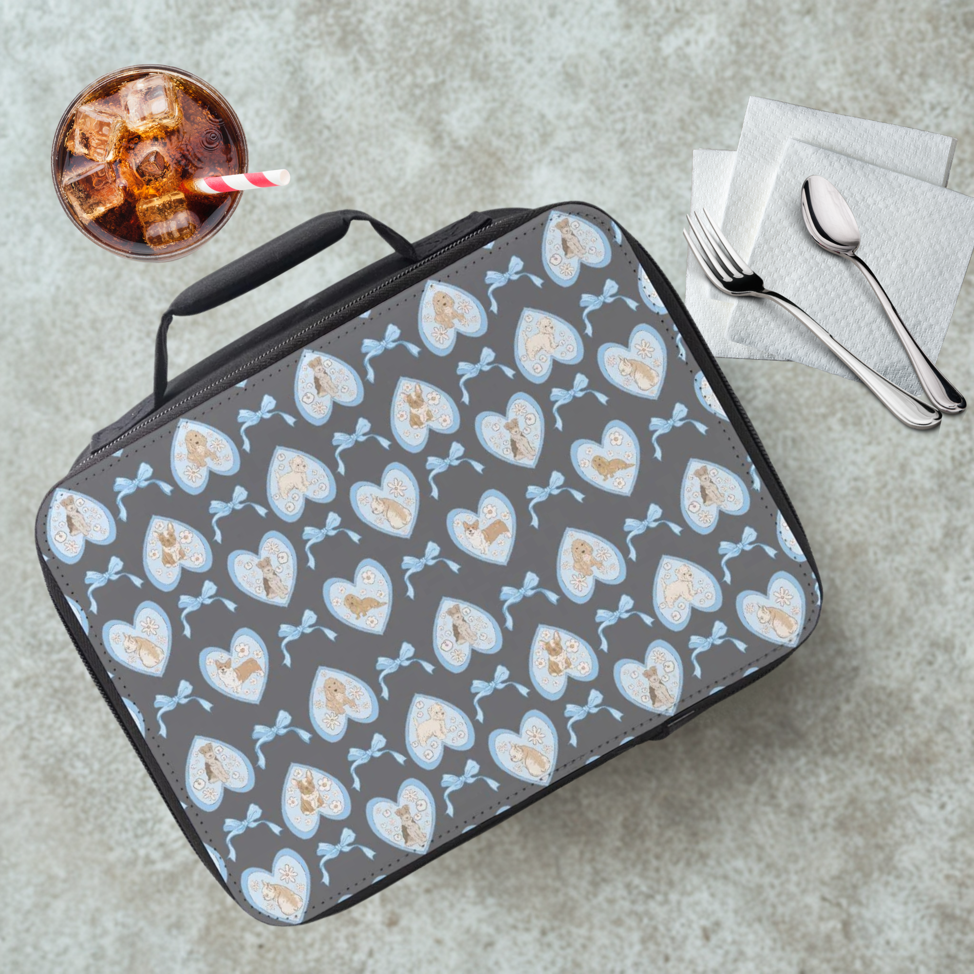 Gray lunch bag with hand drawn heart and dog pattern on a cafeteria table with a drink and utensils.