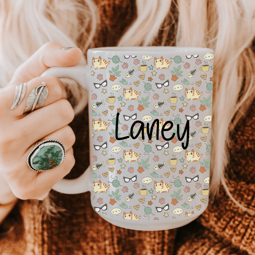 Person holding an 11oz. mug with a cat pattern and 'Laney' custom text.