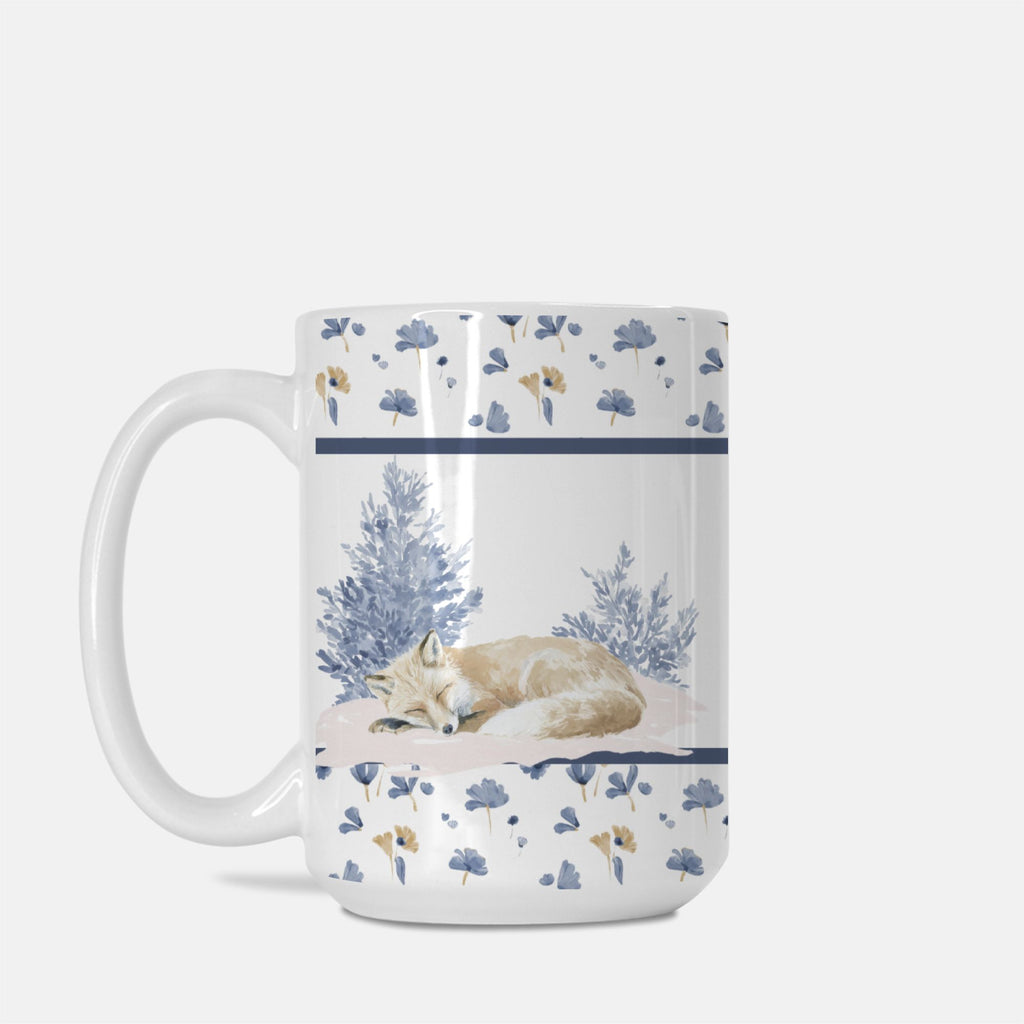 Mug with a design of a sleeping fox surrounded by flowers on a white background
