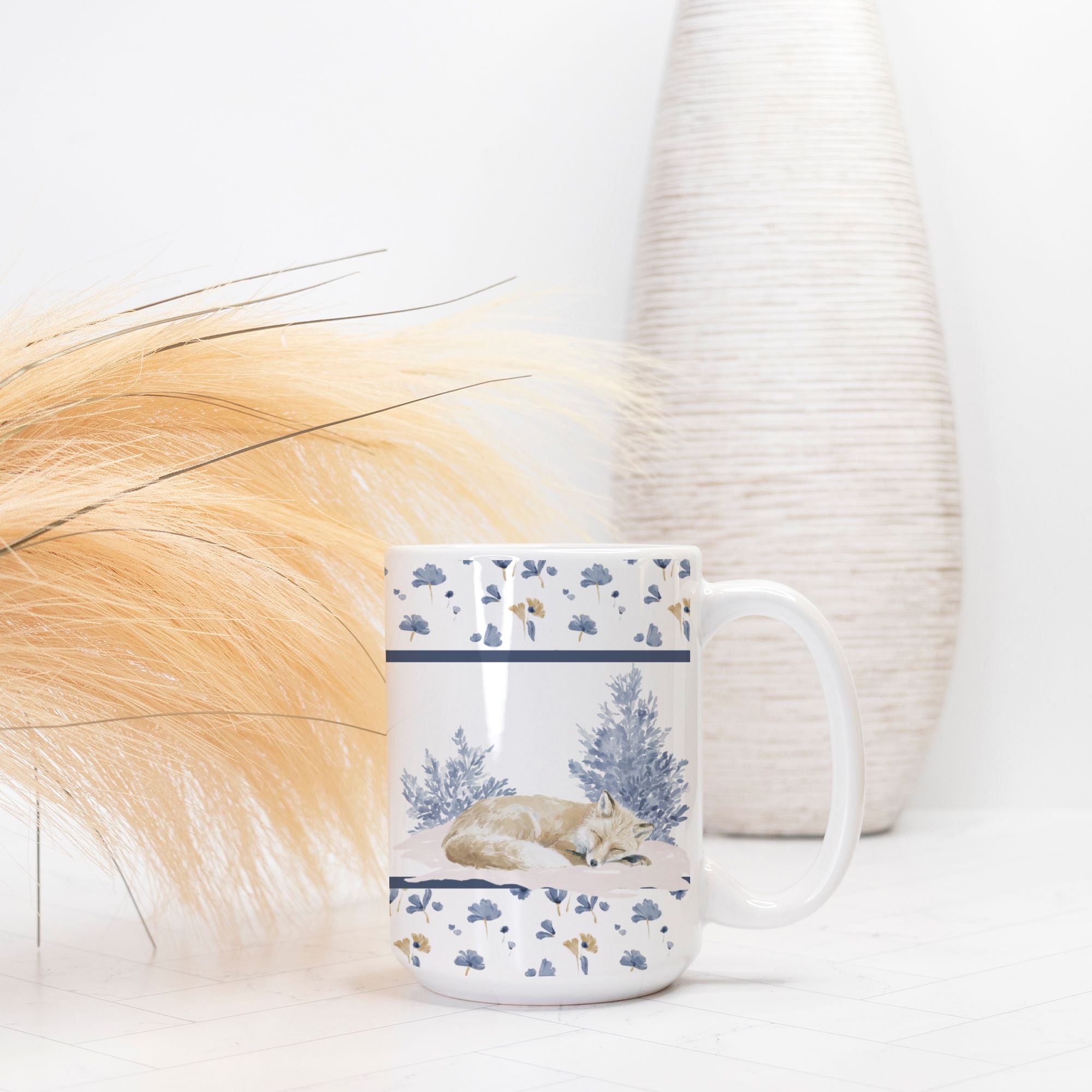 Mug with nature-themed design featuring a sleeping fox, placed on a light surface with a blurred background.