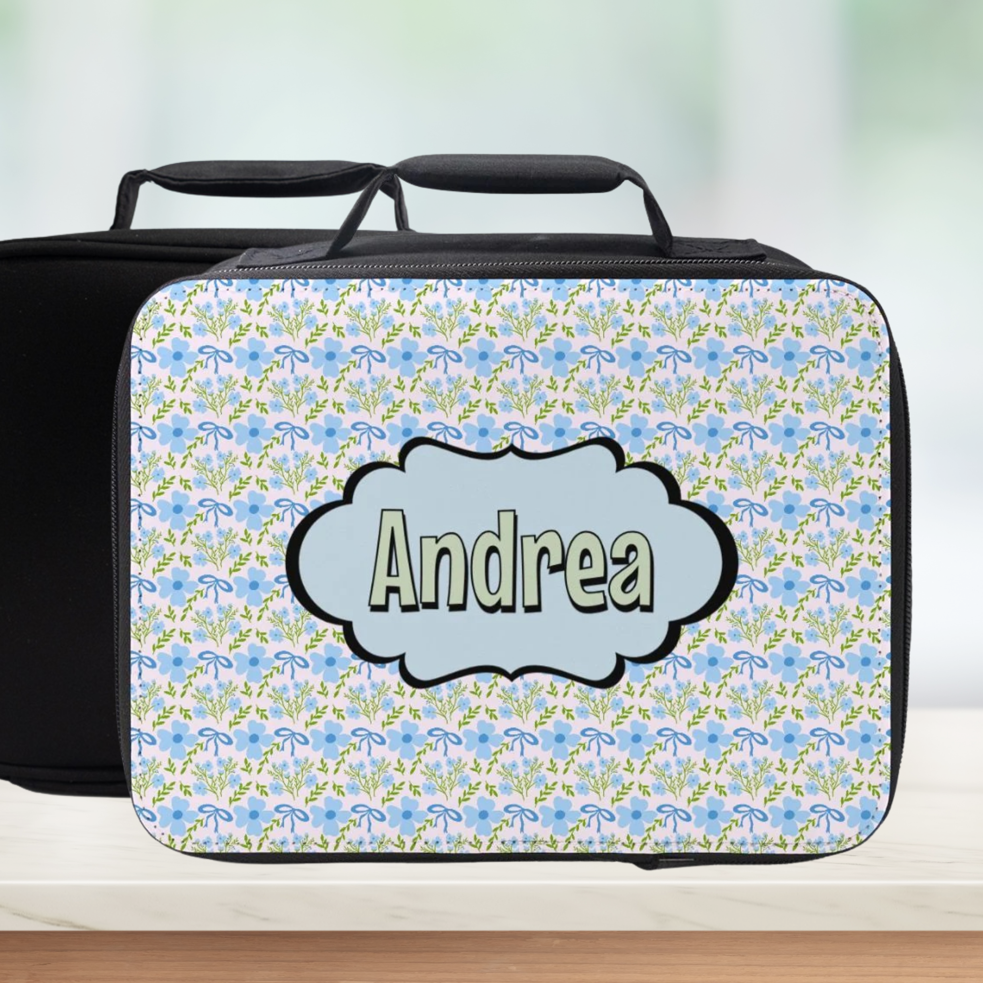 Coquette floral patterned lunch bag with 'Andrea' personalized name on a blurred background