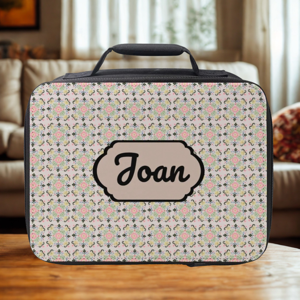 Floral patterned lunch bag with 'Joan' custom text on a wooden coffee table in a cozy living room.