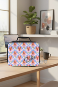 Insulated lunch bag with lobster pattern and 'Lidia' custom text on a desk in an office.