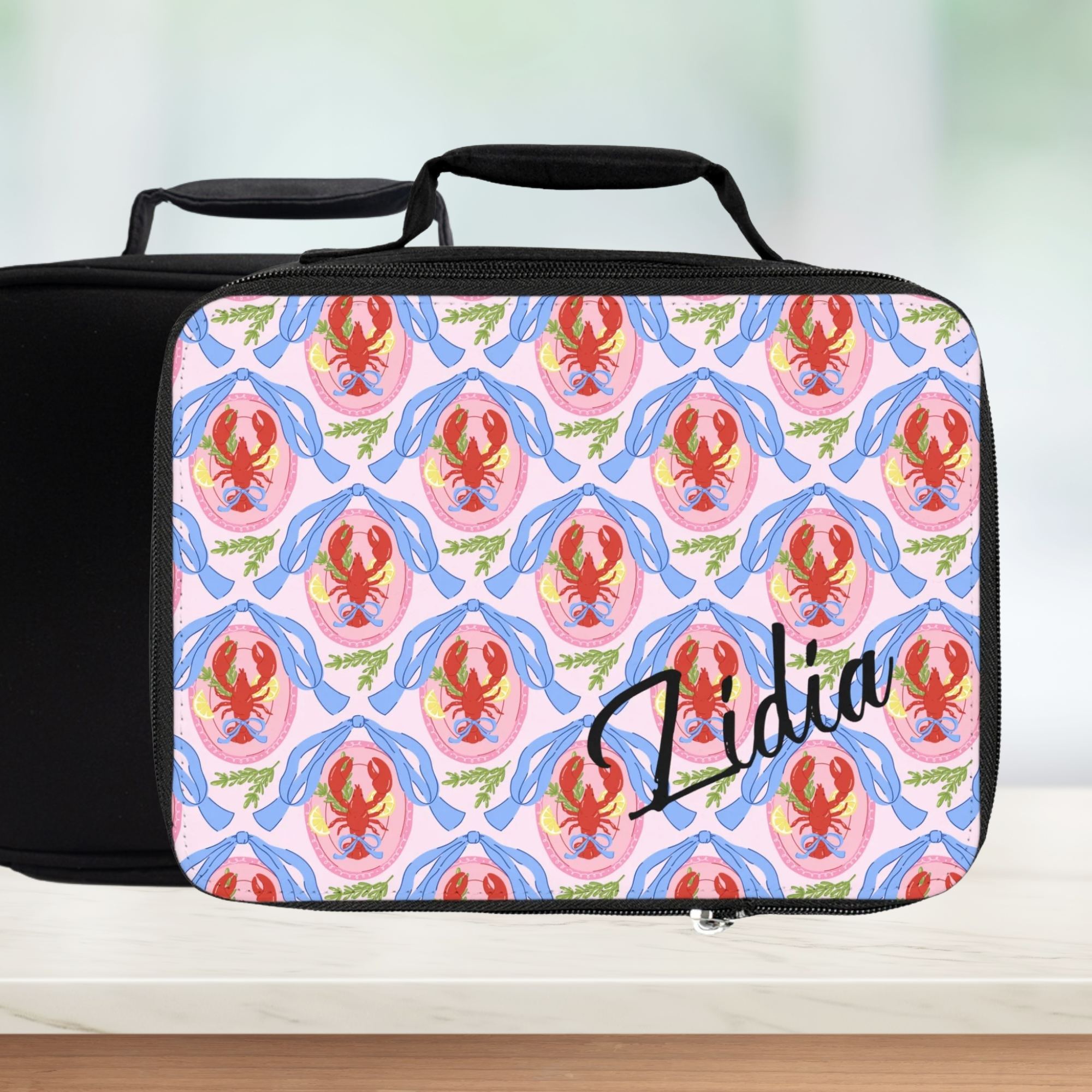 Personalized lunch bag with lobster pattern and name 'Lidia' on a light background