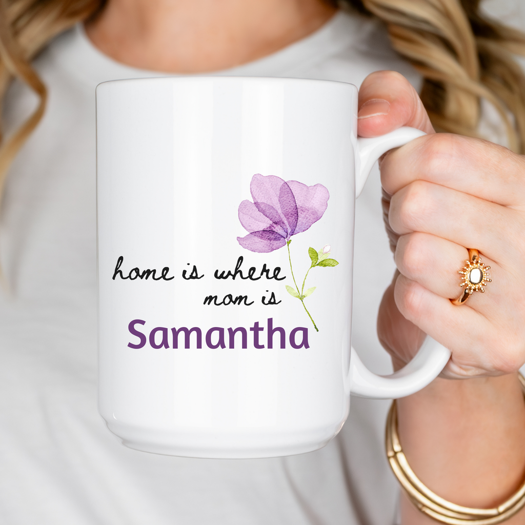 White 15oz. mug with purple flower design and text held by a person