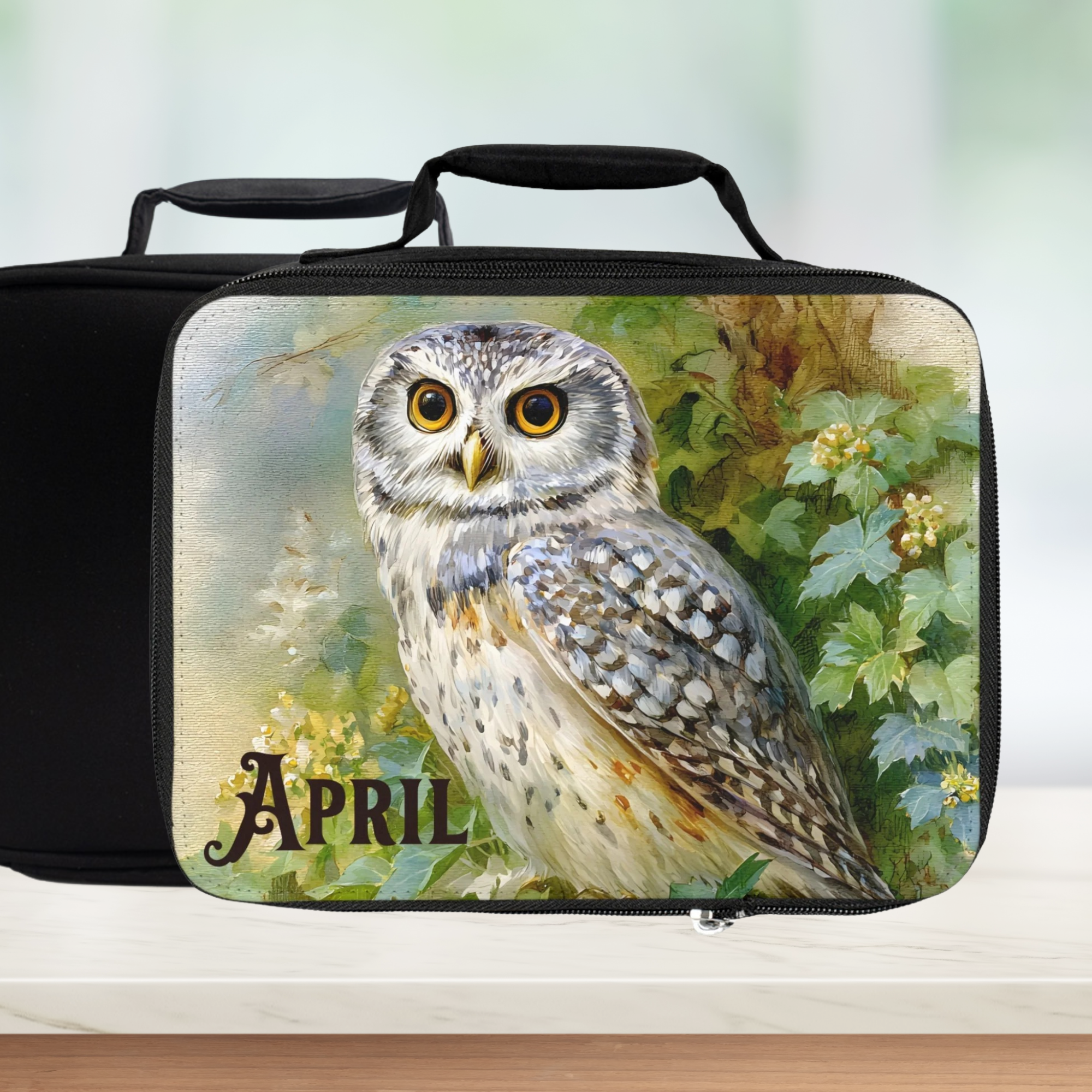 Black lunch bag with an owl design and 'April' text on a floral background