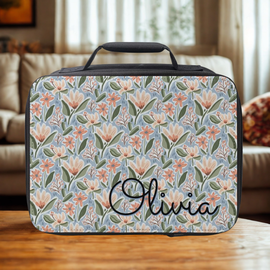 Floral-patterned lunch bag with 'Olivia' custom text on a wooden picnic table.