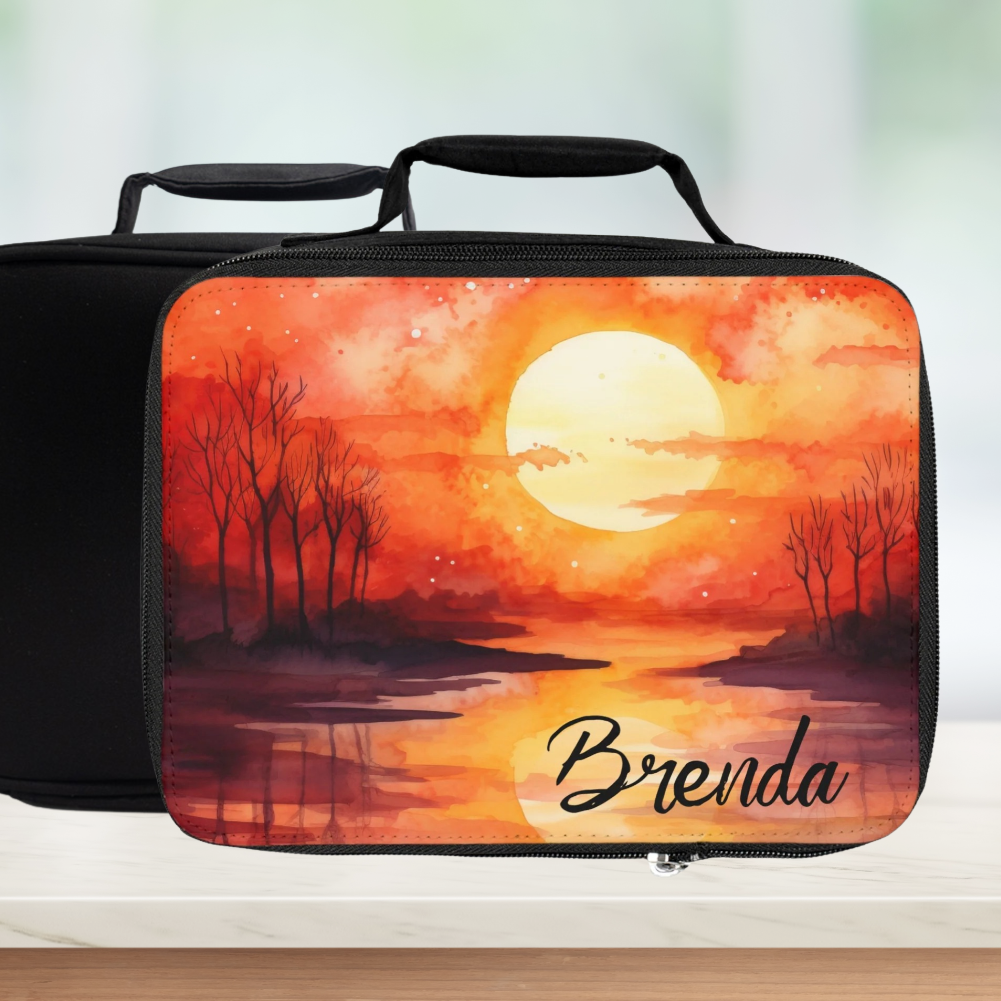 Rectangular lunch bag with sunset design and 'Brenda' text on a blurred background