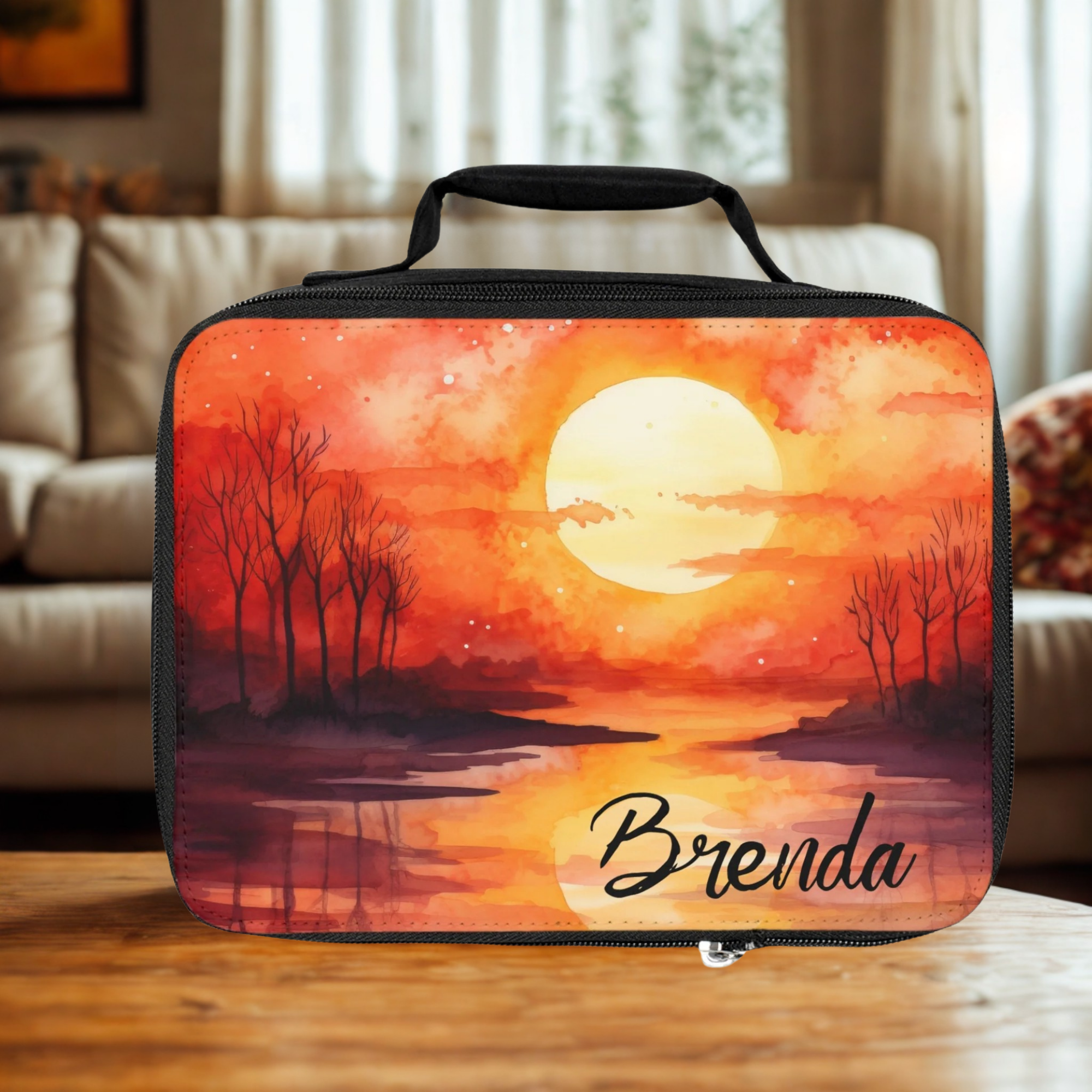  insulated lunch bag with sunset design and 'Brenda' text on a living room table.