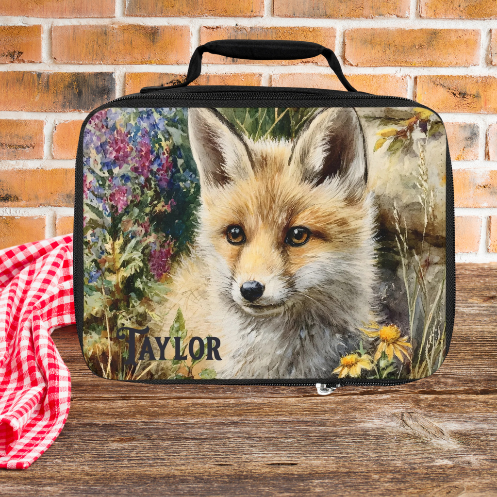  insulated lunch bag with a fox design and 'Taylor' text, placed on a wooden surface with a brick wall background.