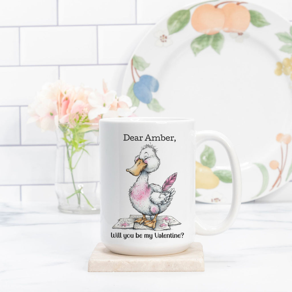 Mug with a cartoon duck holding a heart and text on a white surface with a decorative plate in the background.