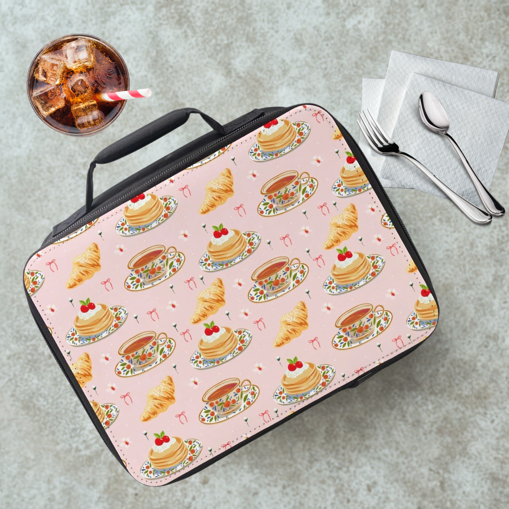 Lunch bag with pastry pattern on a cafeteria table with a drink and utensils.