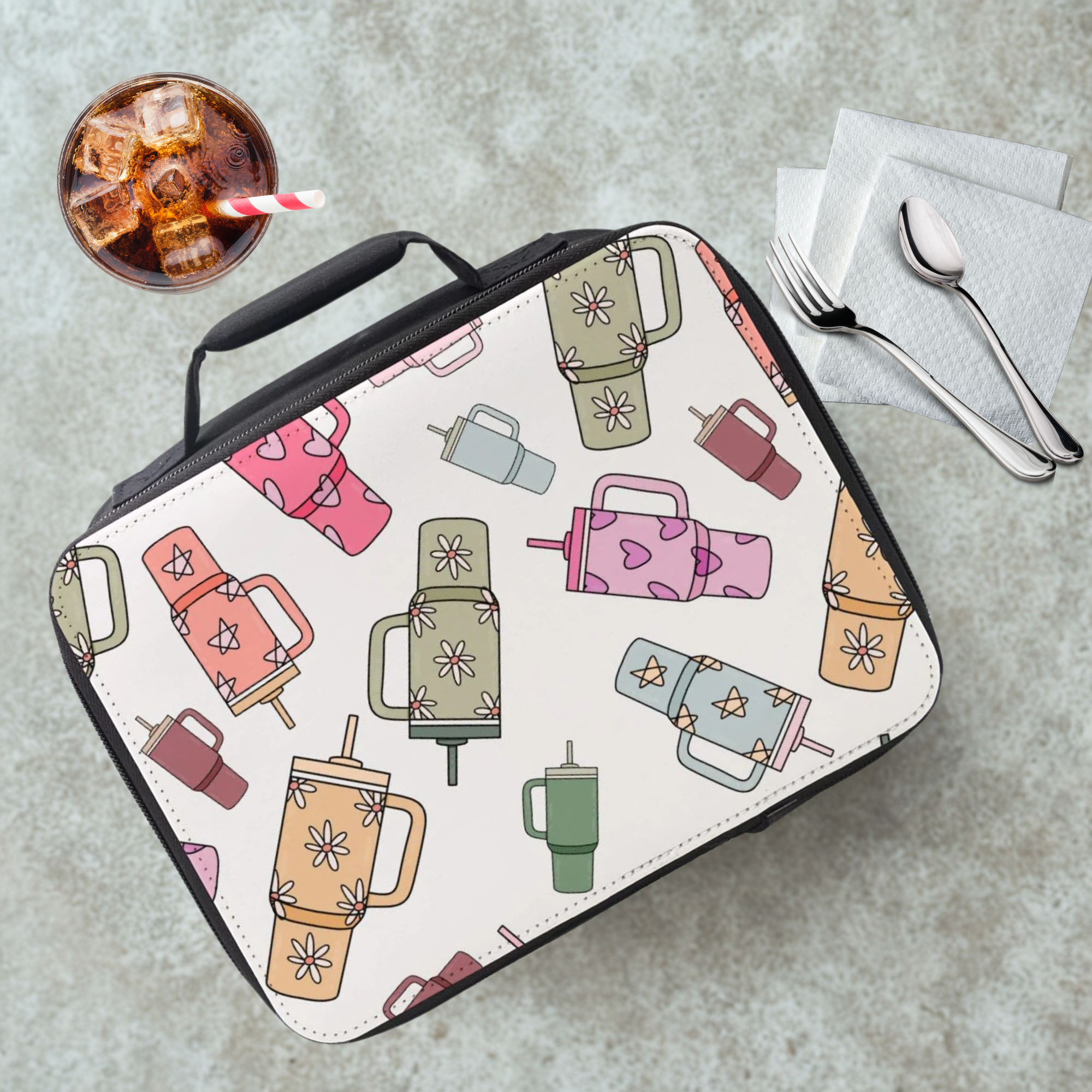 Colorful insulated lunch bag with trendy cup pattern on a cafeteria table with a drink and utensils.