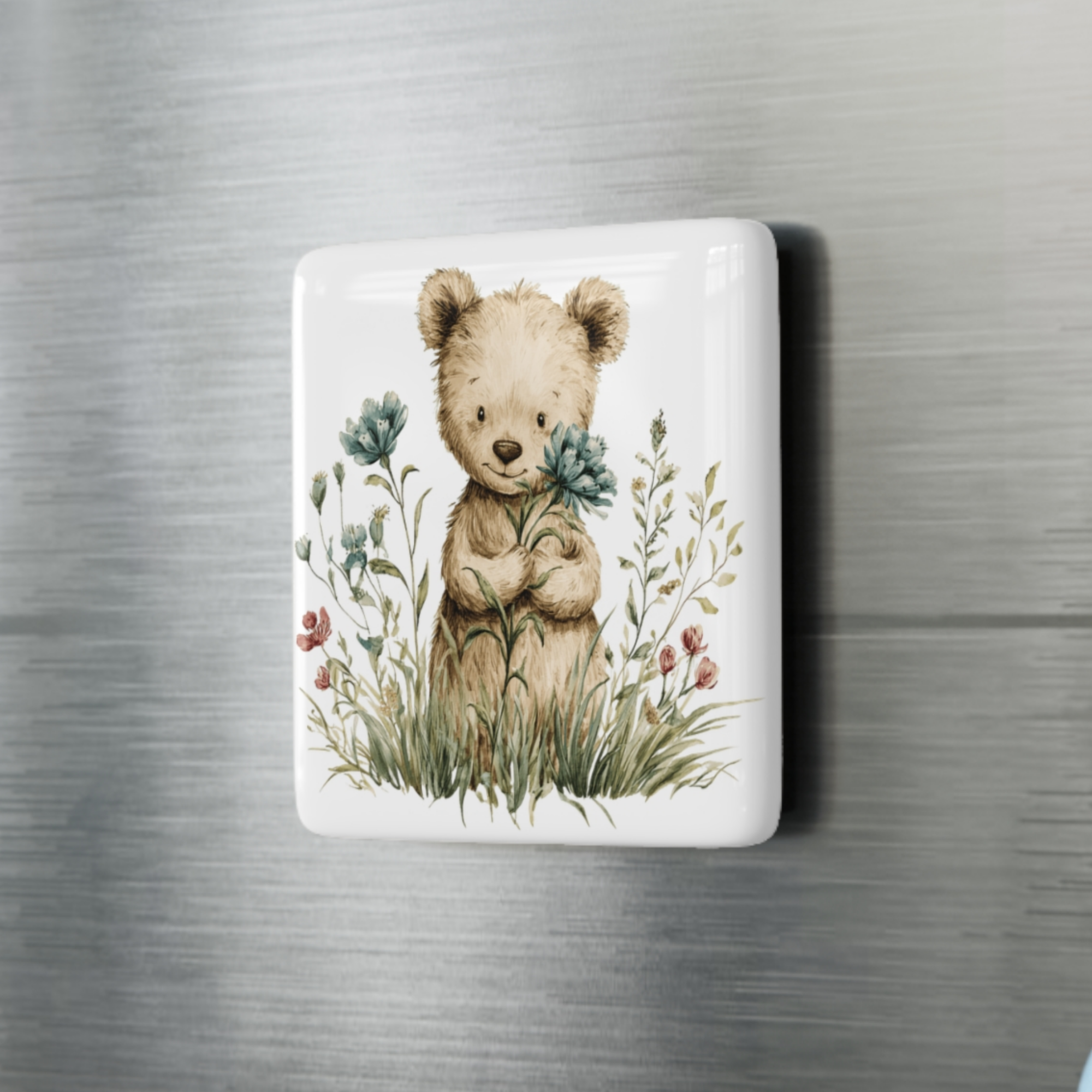 Decorative square porcelain magnet with a teddy bear and floral design on a fridge.