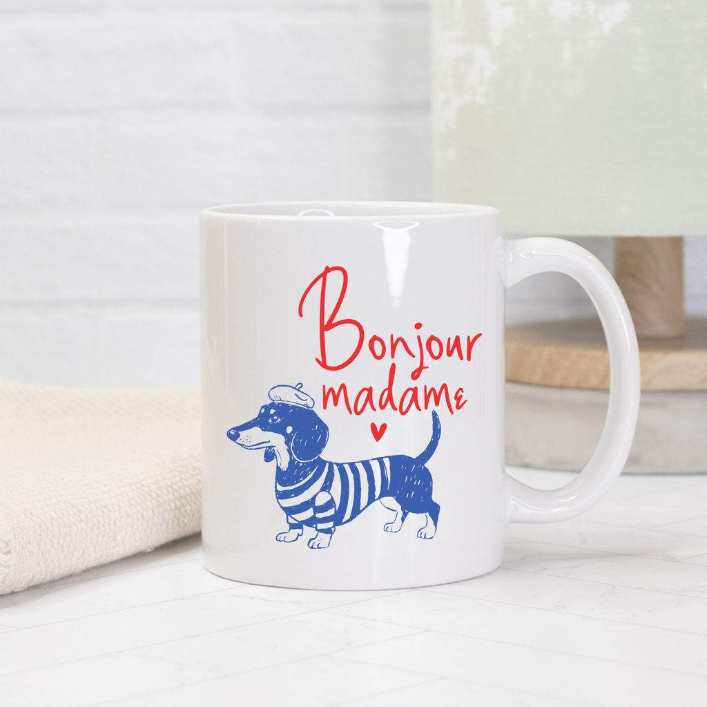 White 11oz. mug with blue dachshund illustration and 'Bonjour madame' text on a white surface.
