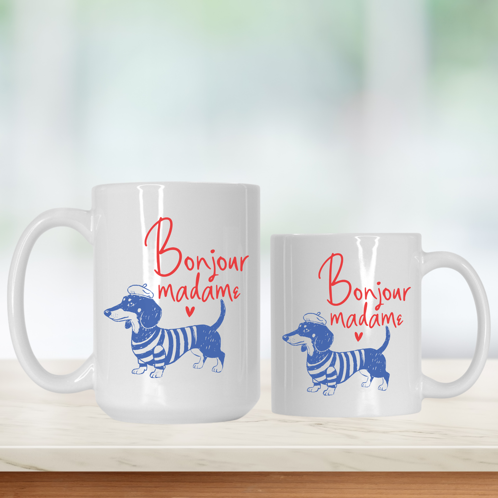 Two white mugs with a dachshund design and 'Bonjour madame' text on a light background.