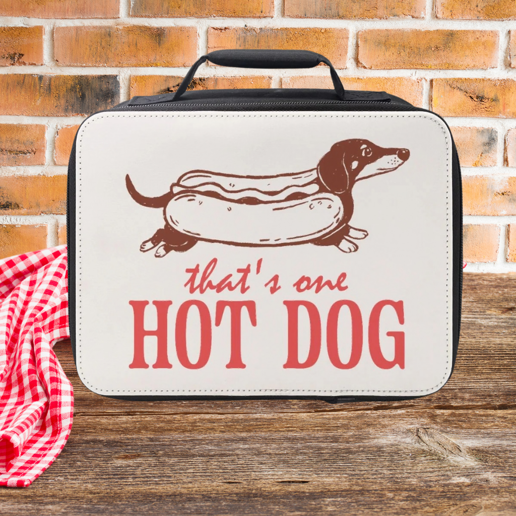 Lunch bag with Dachshund as a hot dog graphic and text 'That's one HOT DOG' on a picnic table against a  brick wall background