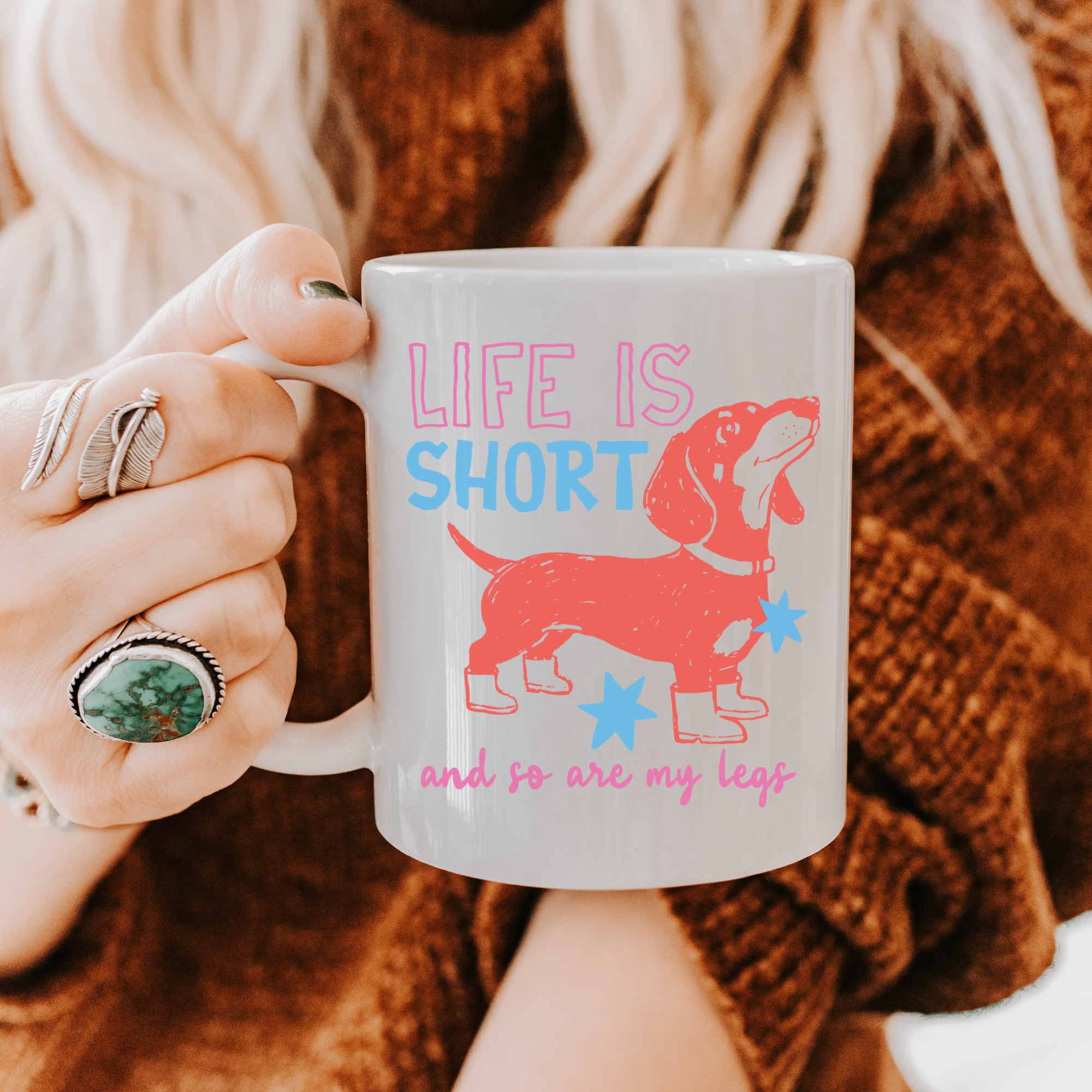 Person holding a 11oz. mug with a dachshund design and text 'Life is short, so are my legs'.