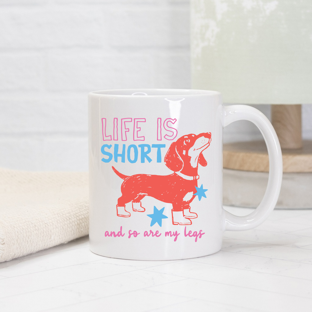 White 11oz. mug with a red dachshund graphic and text 'Life is short and so are my legs' on a light background.