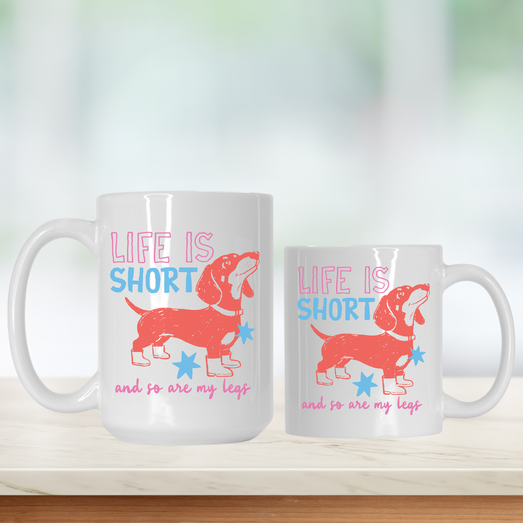 Two white mugs with a dachshund design and text on a light background