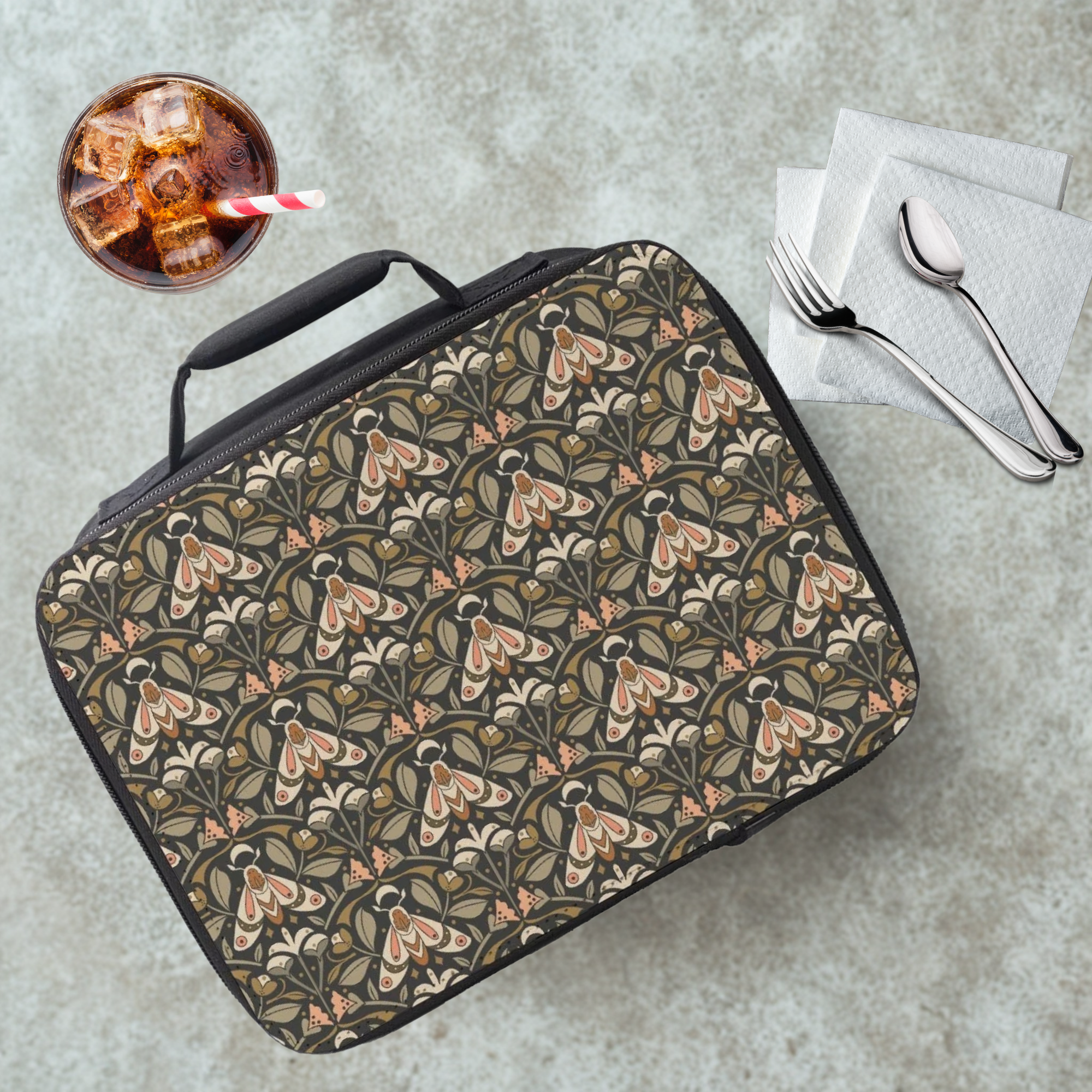 Floral moth patterned lunch bag on a cafeteria table with a drink and utensils.
