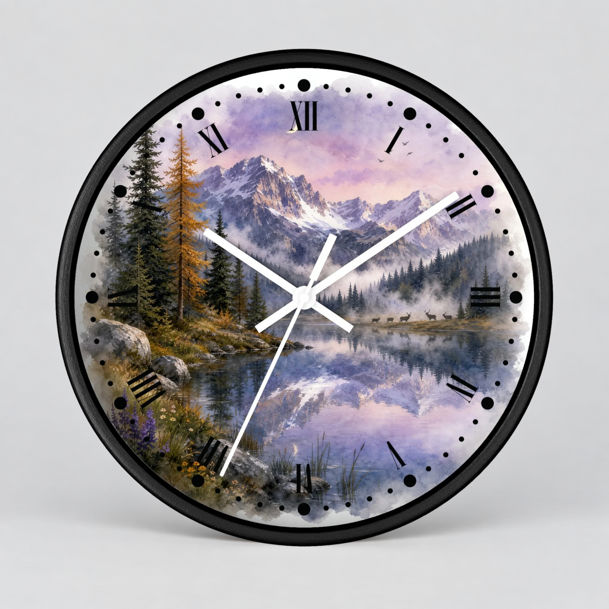 Round wall clock with a black frame and a scenic landscape print featuring mountains, pine trees, a lake, a herd of deer, and a sunset sky. The clock face has black Roman numerals and white hands, photographed against a light gray background.